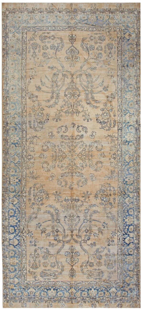 Beige rug featuring detailed blue ornamental patterns and contrasting, faded blue borders.