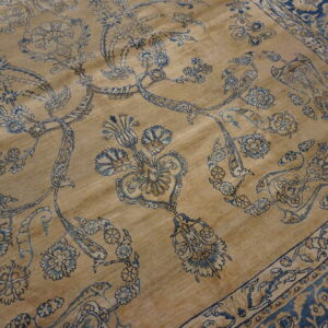 Traditional tan rug with intricate blue and gold floral patterns and a wide blue border visible.