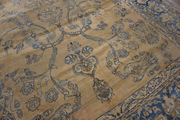 Traditional tan rug with intricate blue and gold floral patterns and a wide blue border visible.