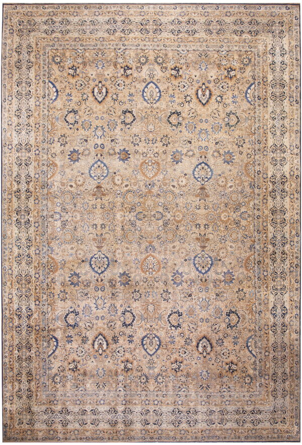 Tan and beige low-pile rug with complex traditional floral designs in dark blue and light brown.