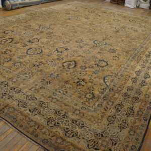 Large traditional gold and navy blue rug with an ornate floral pattern lies on a wooden floor.