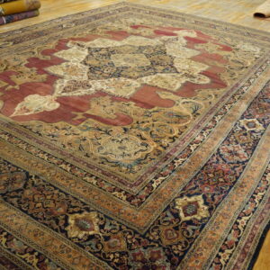 Traditional maroon, navy, and beige medallion rug displayed on light wood plank flooring.