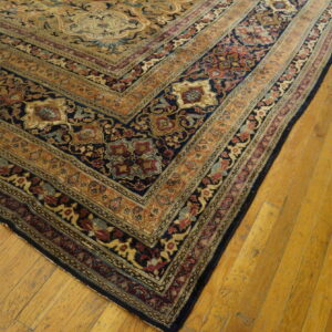 Traditional rug corner displaying detailed navy, gold, and red borders against warm yellow plank flooring.