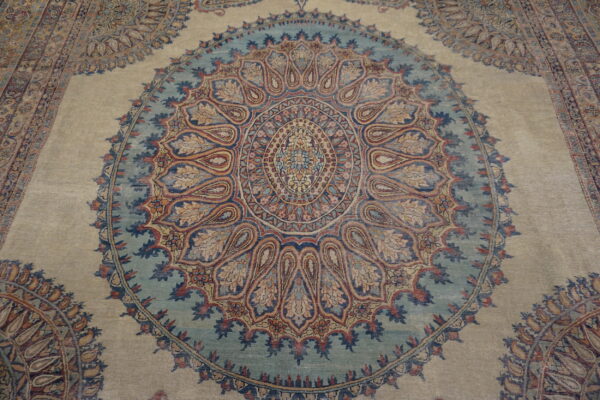 Intricate traditional rug pattern featuring a large blue and multicolor central medallion on a light beige field.