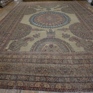 Ornate pale gold rug with intricate blue and red medallions is displayed on a wooden floor.