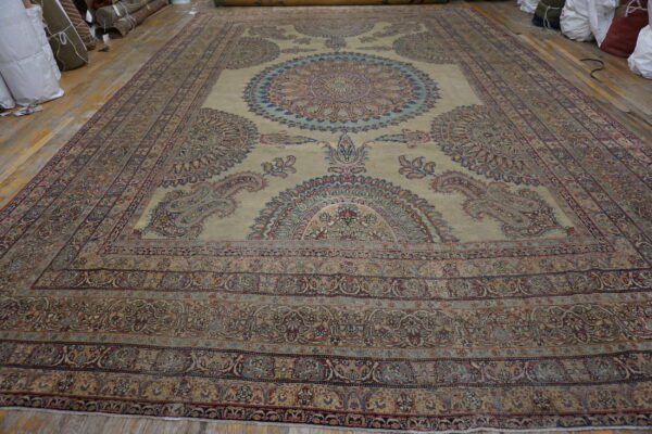 Ornate pale gold rug with intricate blue and red medallions is displayed on a wooden floor.