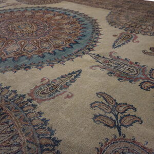 Muted tan rug patterned with large circular teal medallions and rust and blue paisley motifs.