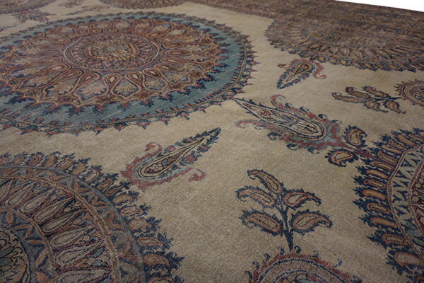 Muted tan rug patterned with large circular teal medallions and rust and blue paisley motifs.