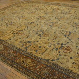 Large ornate rug in gold, rust, and navy blue floral patterns covers hardwood floors.
