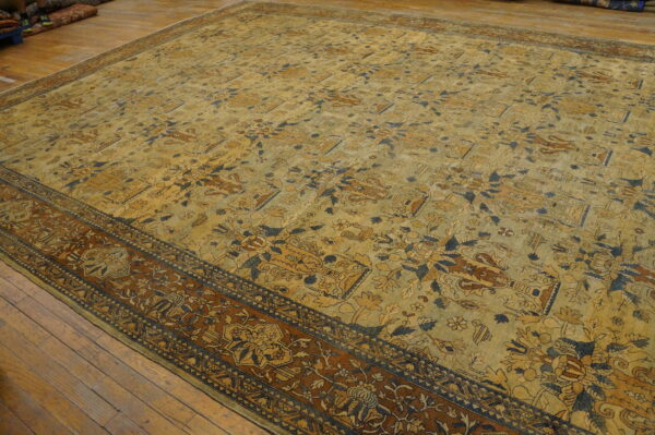 Large ornate rug in gold, rust, and navy blue floral patterns covers hardwood floors.