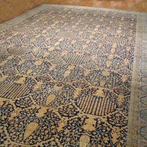 Ornate navy and beige rug with an all-over floral and medallion pattern on hardwood flooring.