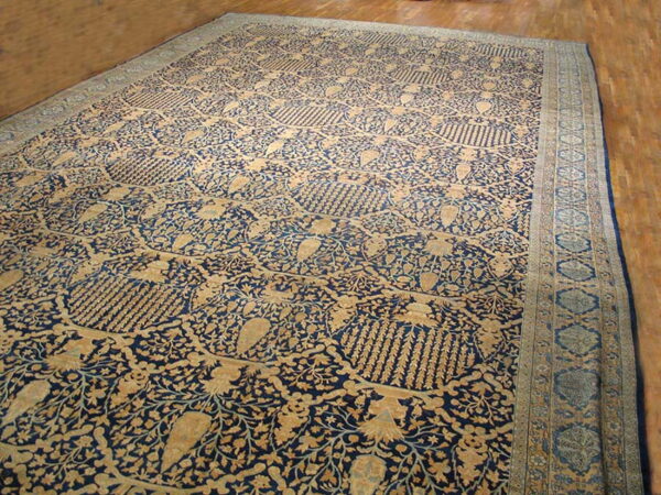 Ornate navy and beige rug with an all-over floral and medallion pattern on hardwood flooring.