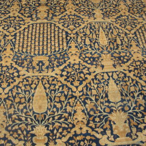 Traditional rug features a detailed tan and gold botanical pattern across a dark blue field.