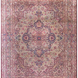 Ornate area rug in faded red, cream, and dark blue with complex floral borders and a central medallion.