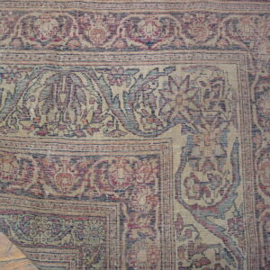 Faded traditional rug with red, blue, and beige floral patterns, peeling back to reveal wood floors.