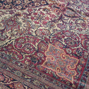 Detailed view of a classic patterned rug in tones of cranberry red, navy, and cream.