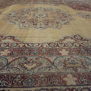 Traditional beige rug with a medallion design and elaborate borders in deep red and navy blue.