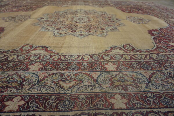 Traditional beige rug with a medallion design and elaborate borders in deep red and navy blue.