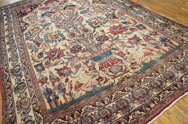 Intricate beige rug featuring a central vase, birds, and dense floral patterns on a wooden floor.