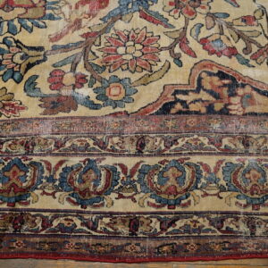 Distressed rug with intricate red and blue floral patterns on a faded beige field, bordered by dense medallions.