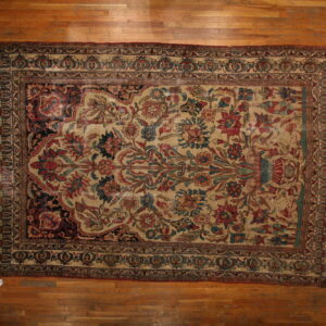 Floral rug with a beige center and red and blue stylized motifs displayed flat on a hardwood floor.