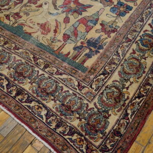 Traditional cream rug corner showing detailed red, blue, and teal borders on yellow wood floors.