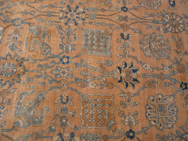 Low-pile rug in dusty peach featuring intricate blue, cream, and brown traditional botanical designs.