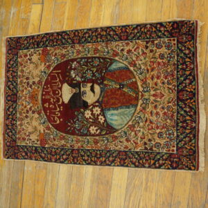 Detailed red, blue, and beige rug featuring a central portrait medallion and intricate scrolling floral design on wood planks.