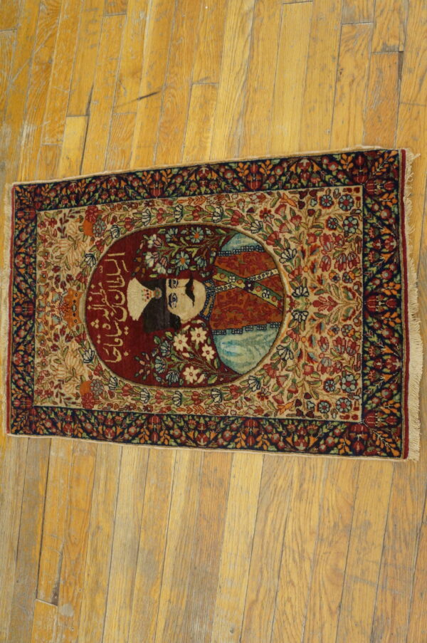 Detailed red, blue, and beige rug featuring a central portrait medallion and intricate scrolling floral design on wood planks.