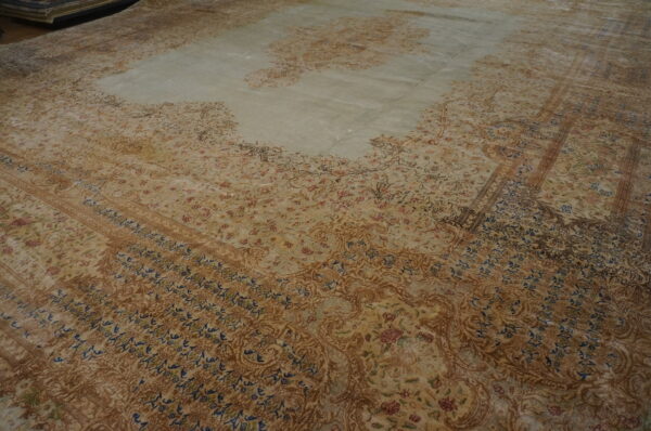 Traditional high-sheen rug in muted green, tan, and brown tones with intricate floral motifs.