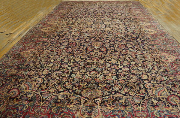 Navy area rug featuring intricate traditional floral and vine motifs displayed on distressed wooden planks.