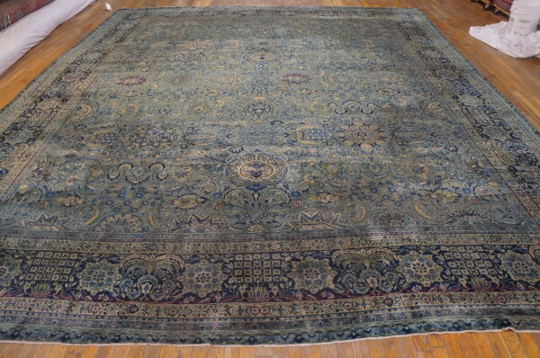 Oversized traditional rug with a detailed blue, teal, and navy floral pattern on hardwood flooring.