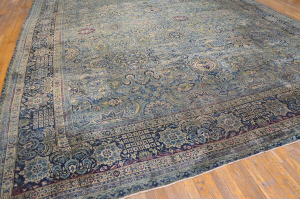 Distressed blue and teal rug with intricate traditional patterns rests on light brown wood planks.