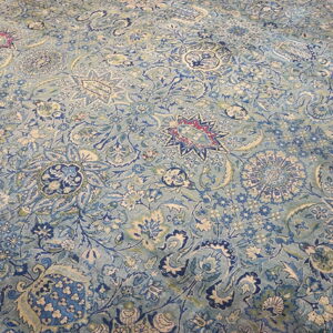 Detailed low-pile rug with a dense traditional pattern featuring blue, aqua, cream, and magenta accents.