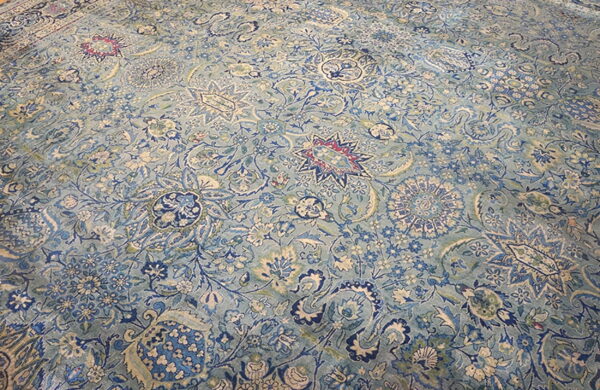 Detailed low-pile rug with a dense traditional pattern featuring blue, aqua, cream, and magenta accents.