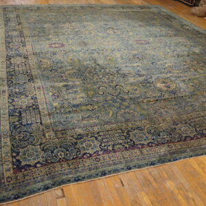 Large area rug featuring a muted blue and sage green all-over floral design with a navy border.