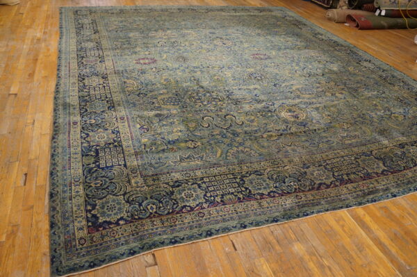 Large area rug featuring a muted blue and sage green all-over floral design with a navy border.