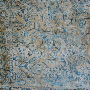 Beige rug featuring an intricate blue and brown botanical pattern and a distressed low pile texture.