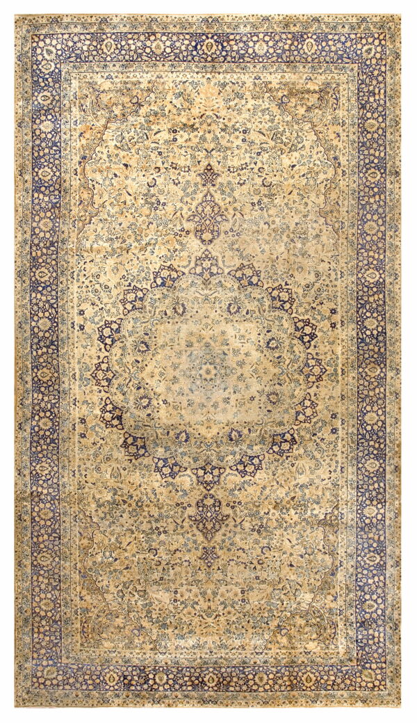 Distressed low-pile rug with a beige field, central medallion, and navy blue complex floral border.