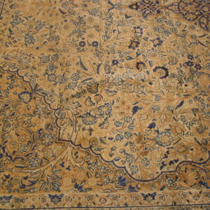 Low pile rug texture showing a busy tan field covered in dark and light blue floral patterns.