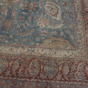 Muted blue rug with intricate floral patterns and multiple borders in faded red, beige, and tan.