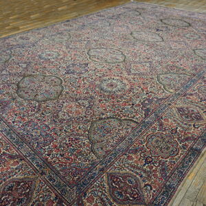 Detailed area rug with red, blue, and cream dense patterns and scattered medallions rests on rustic plank flooring.