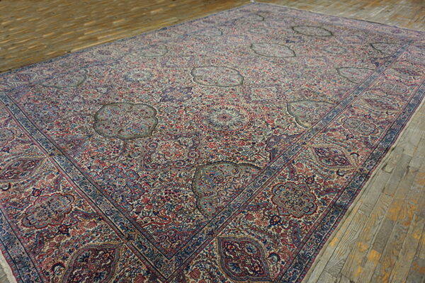 Detailed area rug with red, blue, and cream dense patterns and scattered medallions rests on rustic plank flooring.