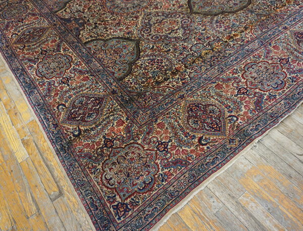 Traditional rug with detailed blue and red floral patterns lies on distressed yellow and gray wood flooring.