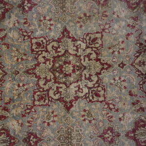 Low-pile rug with a distressed traditional medallion and floral pattern in faded gray, red, and beige.