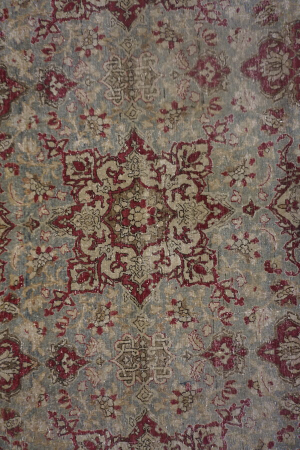 Low-pile rug with a distressed traditional medallion and floral pattern in faded gray, red, and beige.