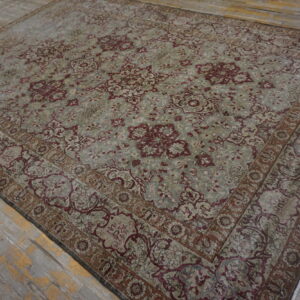 Ornate area rug in muted gray and burgundy with a low pile rests on distressed gray wood flooring.