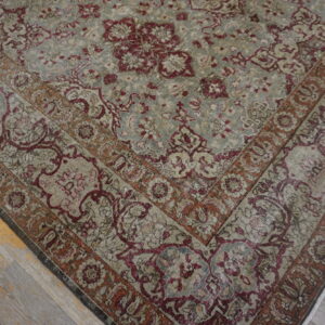 Gray and burgundy traditional rug with distressed floral pattern rests on gray wood flooring.