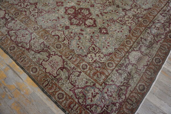 Gray and burgundy traditional rug with distressed floral pattern rests on gray wood flooring.