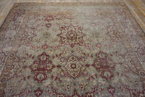 A distressed traditional rug featuring a burgundy and tan floral pattern on a faded blue-gray field.